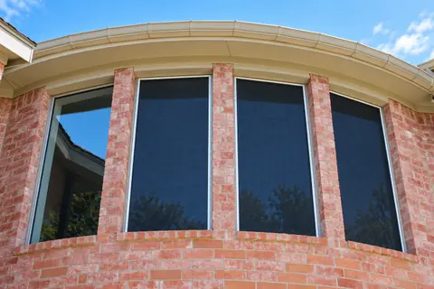 Dark solar screens installed on the windows of a Houston home
