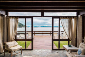 A glass door overlooking a large patio, lake, and mountains.